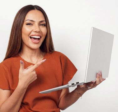 Happy young woman holding laptop computer and pointing at screen against white background