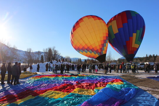 Two hot air balloons inflating beside a spread tarp in winter