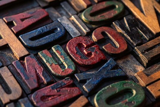 Vintage wooden letterpress type blocks with chipped red, blue and green paint in warm light