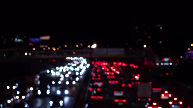 Heavy streams of vehicles moving in opposite directions at night, with white headlights and red taillights illustrating urban congestion, commuter flow and road capacity
