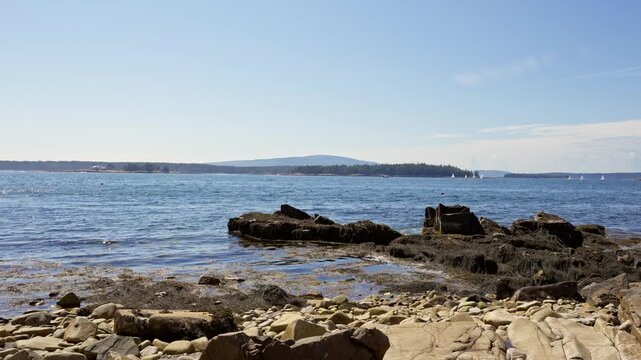 Granite boulders and cobble shore along Schoodic Peninsula looking out across Frenchman Bay toward Mount Desert Island in Acadia National Park, Maine.