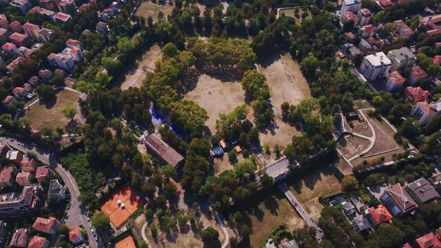 Aerial drone view of Parco della Cittadella in Parma, Italy, showcasing the historic fortress walls, pentagonal park, lush greenery, walking paths, and surrounding cityscape.
