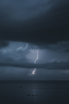 View of a bright lightning bolt striking over the dark sea under a dramatic stormy sky in Merikula, Harju maakond, Estonia.