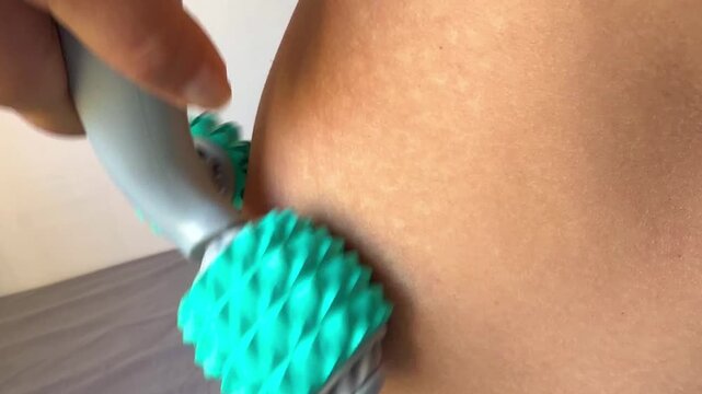 Close up shot of intense self massage on thigh area using spiky roller tool for blood circulation.