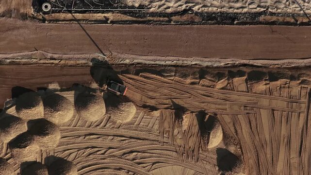 Aerial view of an excavator working on a sandy construction site with visible tire tracks in Enschede, Overijssel, Netherlands.