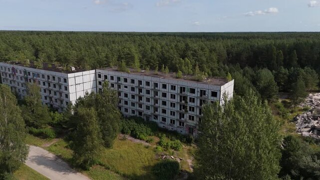 Aerial view of an abandoned Soviet-era apartment building surrounded by dense forest in Irbene, Ventspils novads, Latvia.