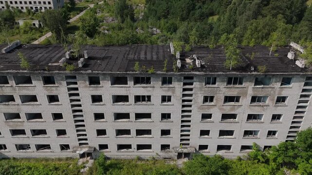 Aerial view of an abandoned Soviet-era apartment building with trees growing on the roof, located in the former military town of Irbene, Ventspils novads, Latvia.