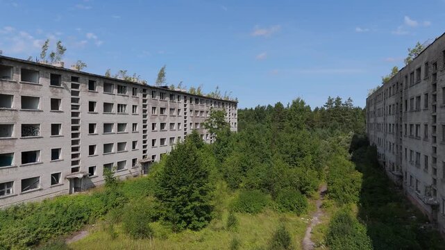 Aerial view of an abandoned Soviet-era apartment building surrounded by overgrown forest and vegetation in Irbene, Ventspils novads, Latvia.