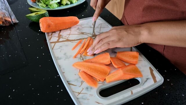 Woman's hands chopping carrots on cutting board