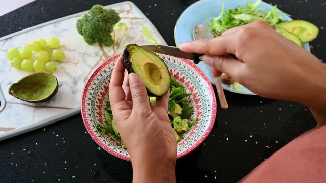 Person preparing a fresh avocado salad for lunch