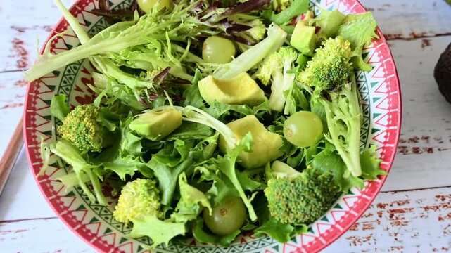 Preparing fresh green salad with avocado and broccoli