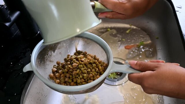 Person rinsing lentils and chickpeas in a kitchen sink