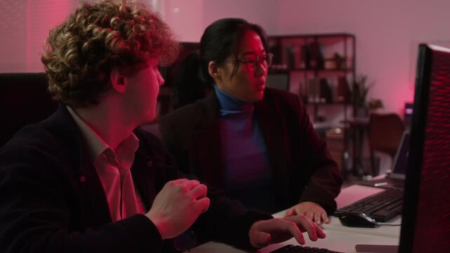 Young Caucasian man and Asian woman cybersecurity analysts troubleshooting server error on computer in office. Footage fits corporate data protection and IT security marketing