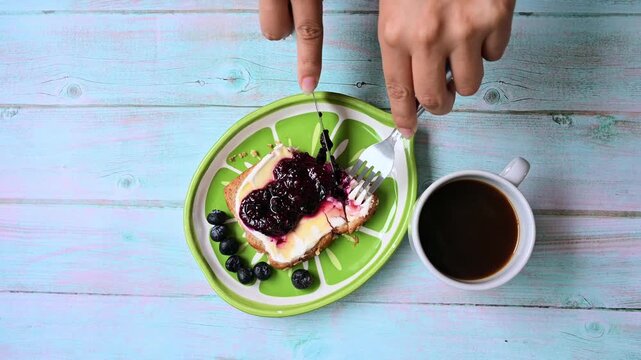 Person eating a healthy blueberry jam toast for breakfast