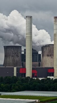 Aerial view of RWE Power AG power plant Niederaussem with cooling towers emitting steam under a cloudy sky in Bergheim, Nordrhein-Westfalen, Germany.
