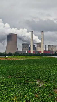 Aerial view of RWE Power AG power plant Niederaussem with cooling towers emitting steam over green fields in Bergheim, Nordrhein-Westfalen, Germany.