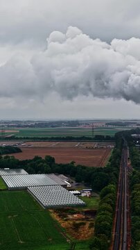 Aerial view of RWE Power AG power plant Niederaussem in the distance with greenhouses and agricultural fields in the foreground in Bergheim, Nordrhein-Westfalen, Germany.