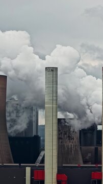 Aerial view of RWE Power AG power plant Niederaussem showing cooling towers emitting steam plumes against a cloudy sky in Bergheim, Nordrhein-Westfalen, Germany.