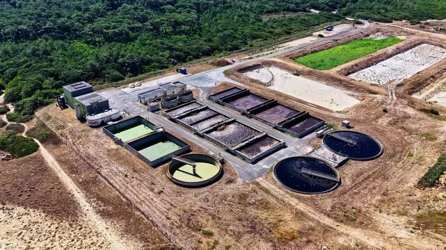 Aerial view of wastewater treatment plant with circular sedimentation tanks and aeration basins near the coastline in Capbreton, Nouvelle-Aquitaine, France.