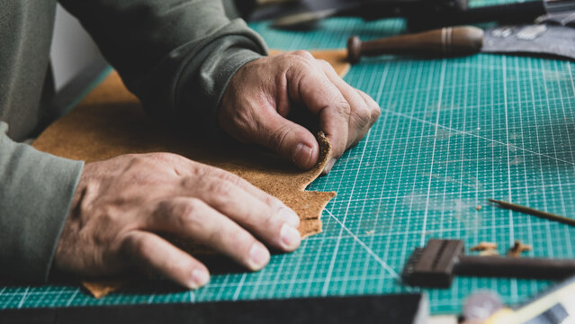 Leather artisan checking the softness and quality of a piece of leather with his hands.