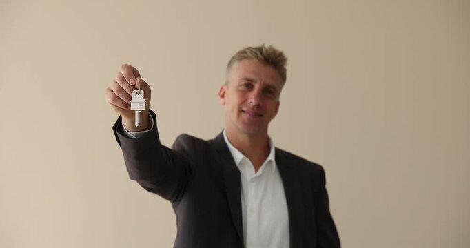 Man with key near beige wall indoors. Office rent