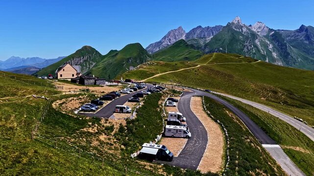 Aerial view of Col d'Aubisque with camper vans parked in a mountain pass surrounded by green slopes and winding roads in Beost, Nouvelle-Aquitaine, France.