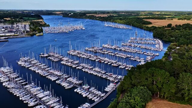 Aerial view of Port d'Arzal-Camoel marina with numerous sailboats moored in rows along the river Vilaine in Arzal, Bretagne, France.