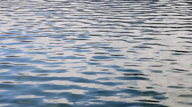 Moving bluish water surface with small waves on the lake
