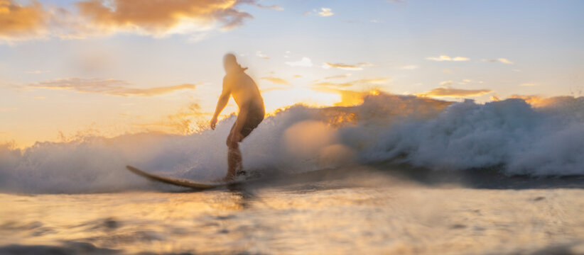 Surfer silhouette riding golden ocean wave during cinematic sunset abstract motion