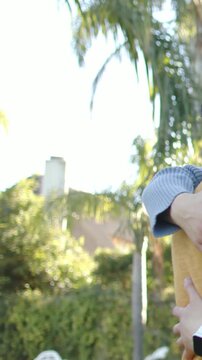 Vertical video: Sun bathing couple hugging lovingly in yard, yellow sweater, smartwatch, copy space