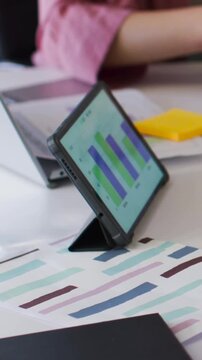 Vertical video: Camera widening team checking swatch with green pencil office pink shirt tablet