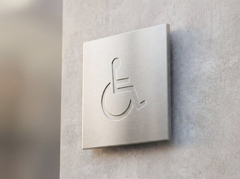 Modern metal anti microbial handicap symbol sign mounted on a textured concrete wall in a public building
