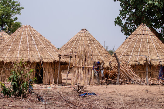 View of traditional thatched-roof huts in a rural village setting with wooden structures and dry earth ground in Bauchi, Bauchi, Nigeria.