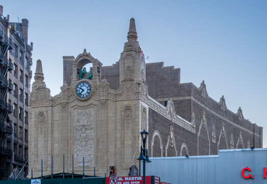 Jersey City, NJ - US - Oct 7, 2026 : A side view of the Loew's Jersey Theatre reveals its clock, towers, sculpted figures, decorative stone facade and long brick exterior beside neighboring buildings.