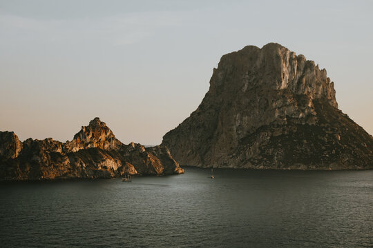 View of Es Vedra, a dramatic limestone rock formation rising from the Mediterranean Sea, illuminated by the warm light of the golden hour, Ibiza, Balearic Islands, Spain.