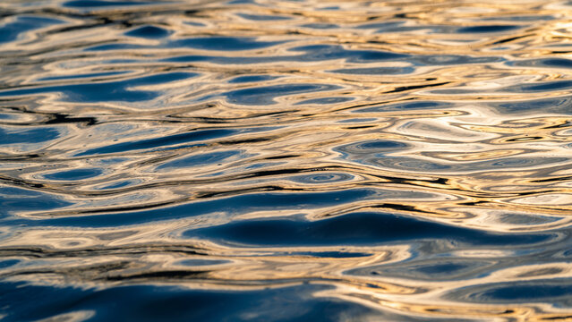 View of golden sunlight reflecting on the rippling surface of the sea in Newquay, England, United Kingdom.