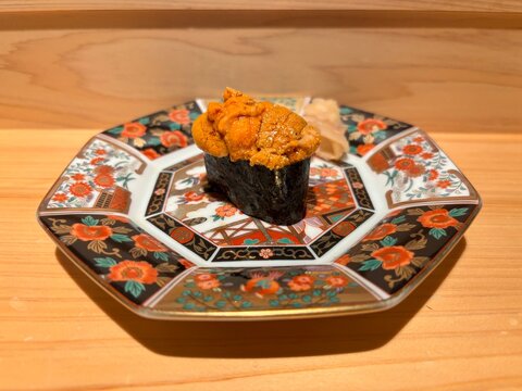 A single piece of premium sea urchin uni gunkan maki sushi on a traditional Japanese plate