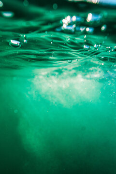 View of turquoise sea water with bubbles and light refraction beneath the surface in Newquay, England, United Kingdom.