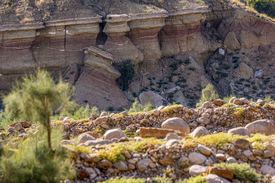 View of the rugged, layered rock formations of the Sulaiman Mountains with sparse vegetation and rocky terrain in the foreground in De-excluded Area Dera Ghazi Khan, Punjab, Pakistan.