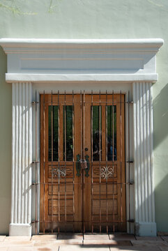 View of a wooden double door with a decorative metal security gate and white fluted columns in Arizona, United States.