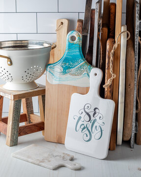 An assortment of cutting boards with a colander on a stool. 