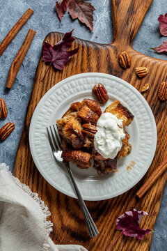 Brown Sugar Butter Pecan French Toast with whip cream on a wooden cutting board.
