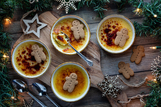 Above view of servings of Creme Brulee topped with gingerbread men biscuits.