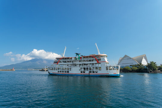 夏の青空と桜島を背景に錦江湾を航行するフェリーとかごしま水族館