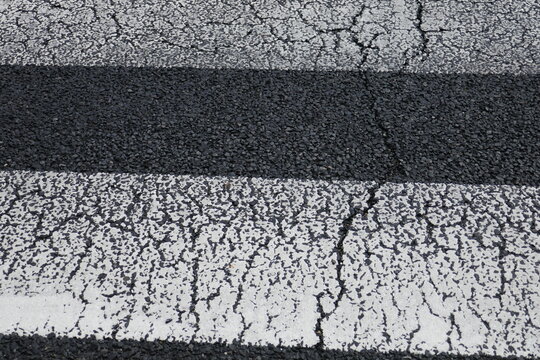 劣化した横断歩道の白線と黒い路面