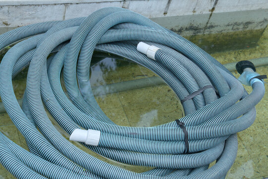 Coiled black and blue striped flexible corrugated hose or pipe with a long flexible striped industrial hose coiled neatly on a concrete surface 