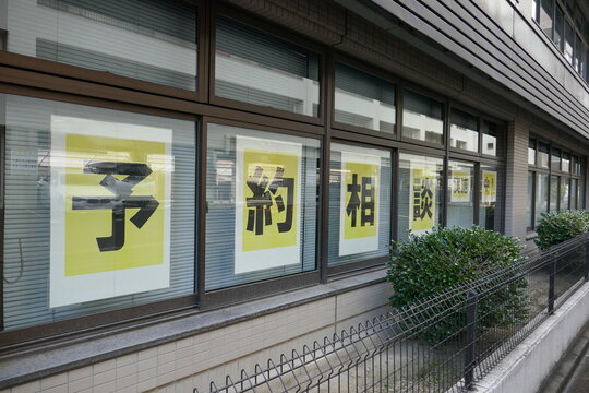 予約相談の文字が貼られた建物の窓