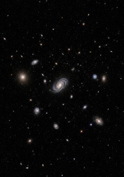 The image displays a stunning deep-space photograph showcasing a cluster of galaxies against a dark, starry background.