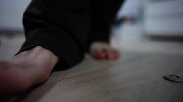 室内のフローリングを裸足で歩く男性の足元クローズアップ