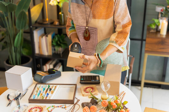 Mature Asian woman using barcode reader scan handcrafted jewelry package